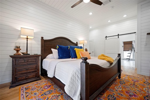 bedroom featuring light wood-style flooring, a barn door, recessed lighting, wooden ceiling, and a ceiling fan