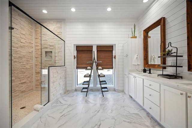 full bathroom featuring a stall shower, recessed lighting, double vanity, marble finish flooring, and wood walls