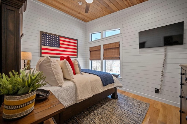 bedroom featuring wooden walls, wood ceiling, wood finished floors, and a ceiling fan
