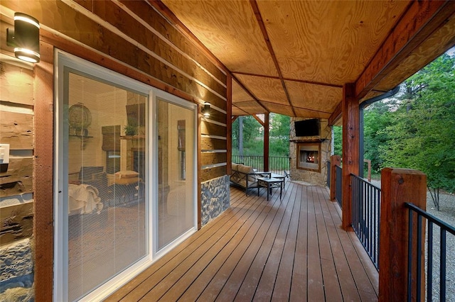 wooden terrace featuring an outdoor stone fireplace