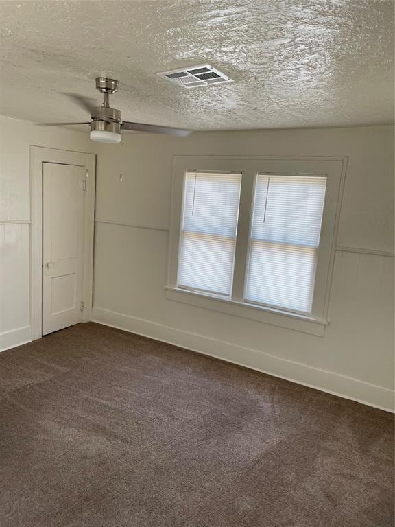 carpeted spare room featuring ceiling fan and a textured ceiling