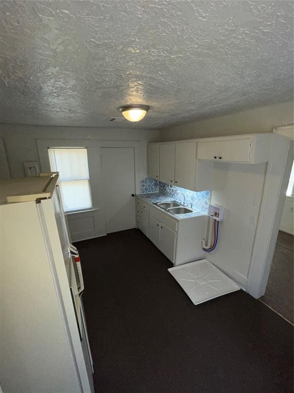 kitchen with sink, a textured ceiling, white cabinets, and white refrigerator