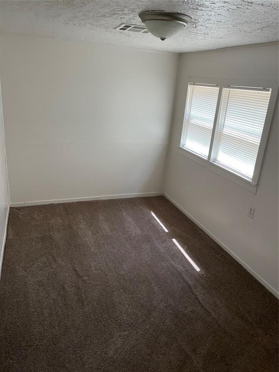 carpeted empty room featuring a textured ceiling