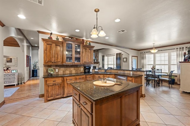 329826 E Hwy 66, Wellston, OK 74881 - kitchen with arched walkways, brown cabinetry, stainless steel dishwasher, light tile patterned flooring, and crown molding