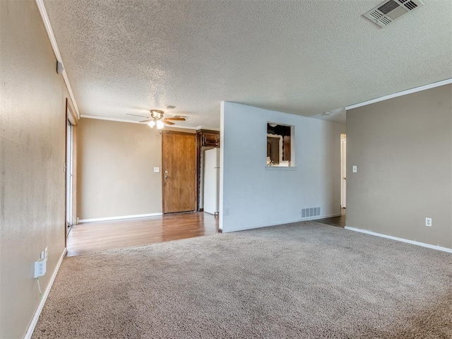 carpeted spare room with a textured ceiling, ornamental molding, and ceiling fan