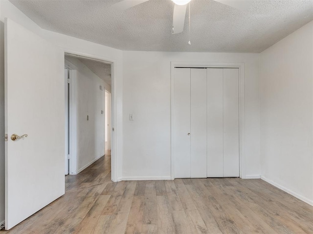 unfurnished bedroom featuring ceiling fan, a textured ceiling, light hardwood / wood-style floors, and a closet