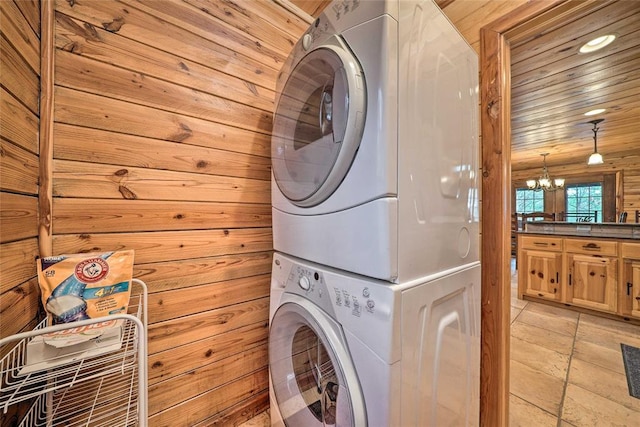 washroom with stacked washing maching and dryer, wooden walls, a notable chandelier, and wood ceiling