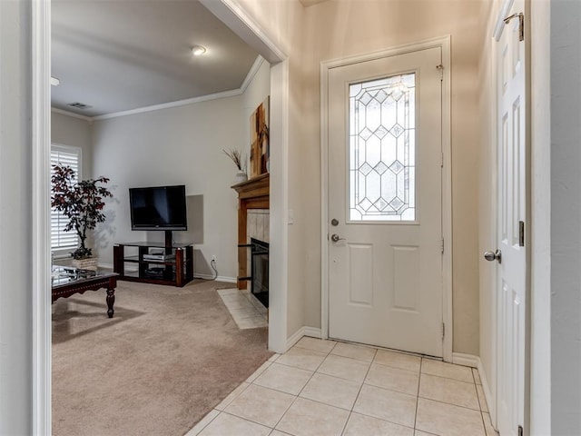 foyer entrance with a tiled fireplace, ornamental molding, and light colored carpet