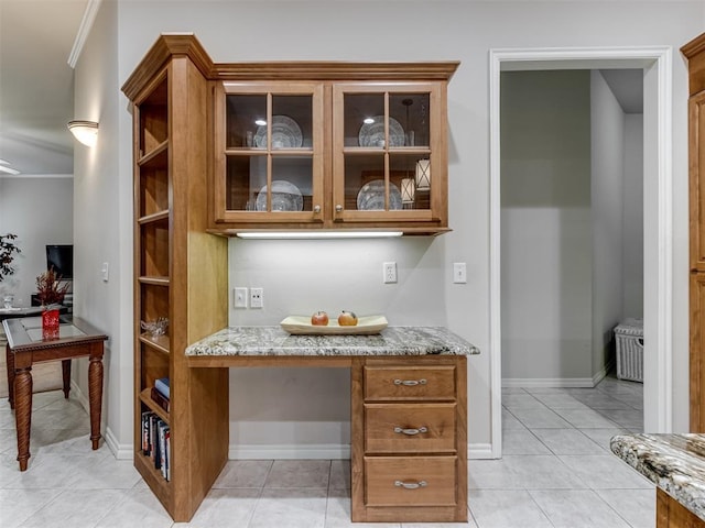 bar with built in desk, light stone countertops, and light tile patterned flooring