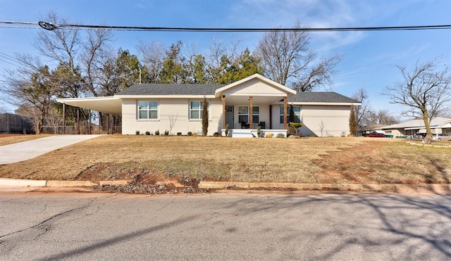 ranch-style house featuring a carport, a porch, concrete driveway, and a front yard