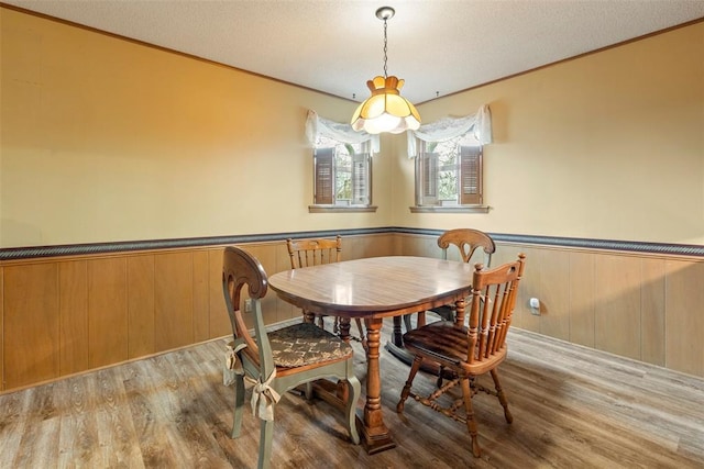 dining room featuring crown molding, a textured ceiling, and light wood-type flooring