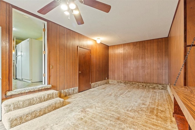 carpeted spare room featuring ceiling fan and wood walls