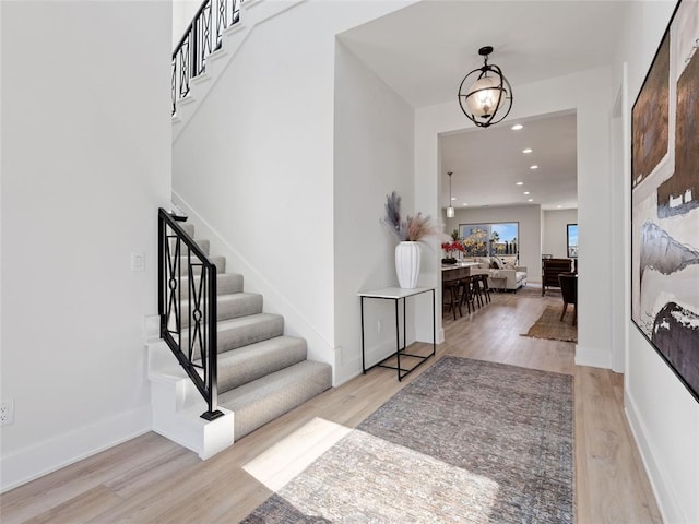 foyer featuring stairs, recessed lighting, an inviting chandelier, and wood finished floors