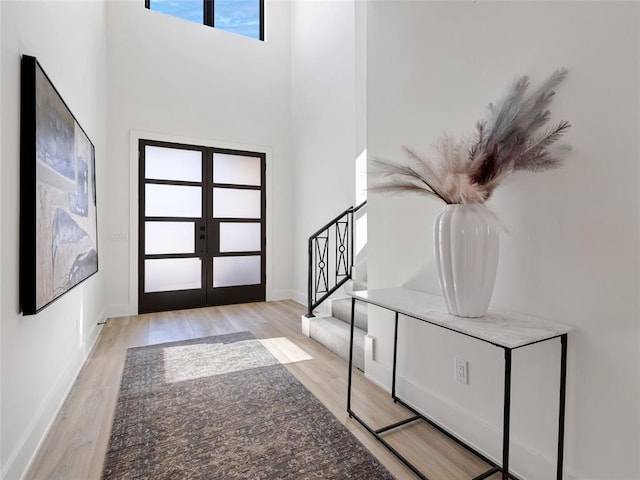 foyer entrance with french doors, stairway, baseboards, and wood finished floors