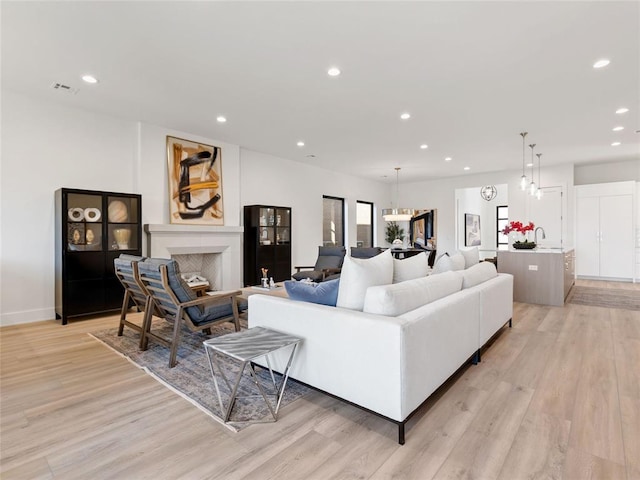 living room with light wood finished floors, a fireplace, visible vents, and recessed lighting