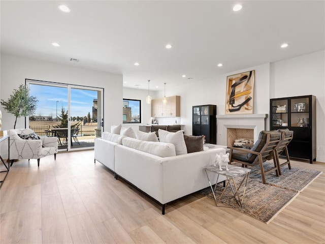 living room with light wood finished floors, a fireplace, visible vents, and recessed lighting