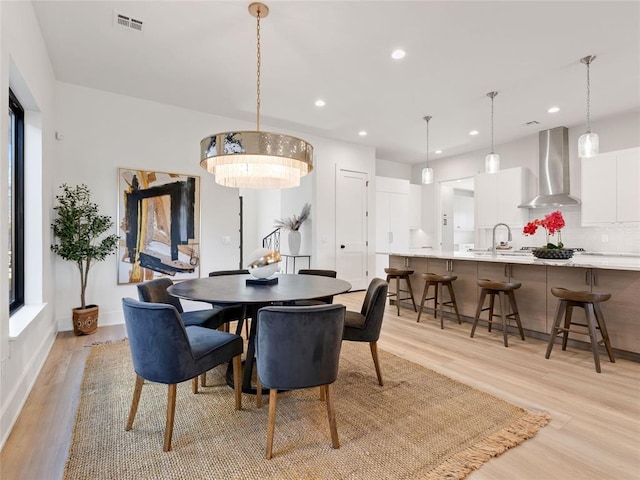 dining room featuring light wood finished floors, baseboards, visible vents, and recessed lighting