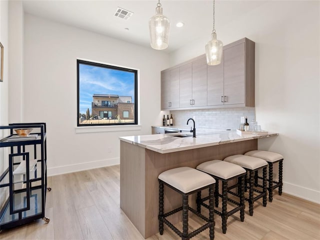 kitchen featuring tasteful backsplash, a breakfast bar, visible vents, and a peninsula