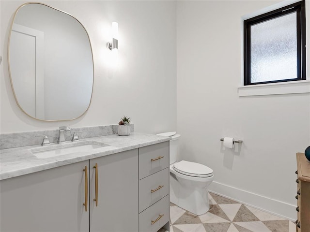 half bath featuring toilet, vanity, and baseboards