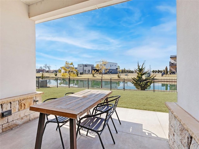 view of patio featuring a water view, fence, and outdoor dining area