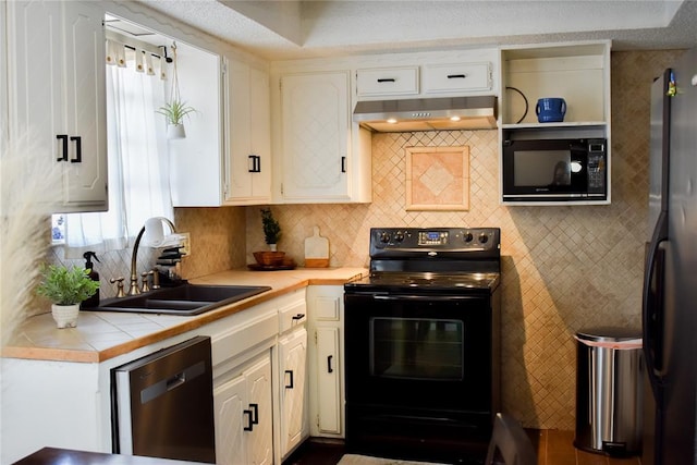 kitchen featuring tasteful backsplash, sink, white cabinets, tile counters, and black appliances