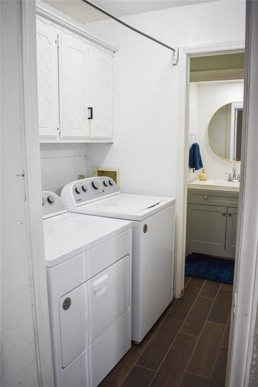 clothes washing area with sink, washing machine and dryer, and cabinets