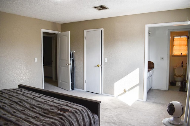 bedroom with light colored carpet and a textured ceiling