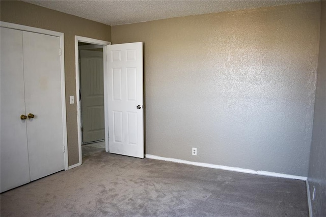 unfurnished bedroom featuring a closet, a textured ceiling, and carpet