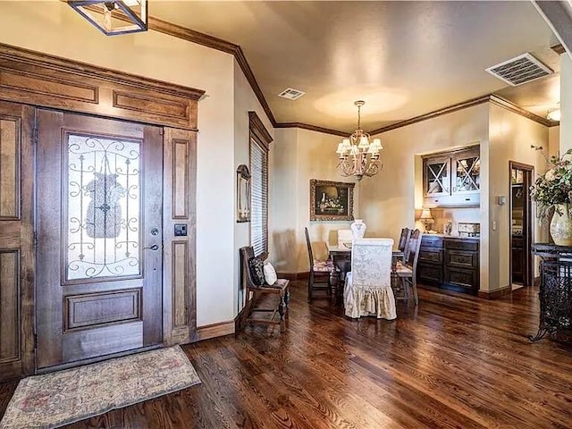 entryway with ornamental molding, dark hardwood / wood-style floors, and a notable chandelier