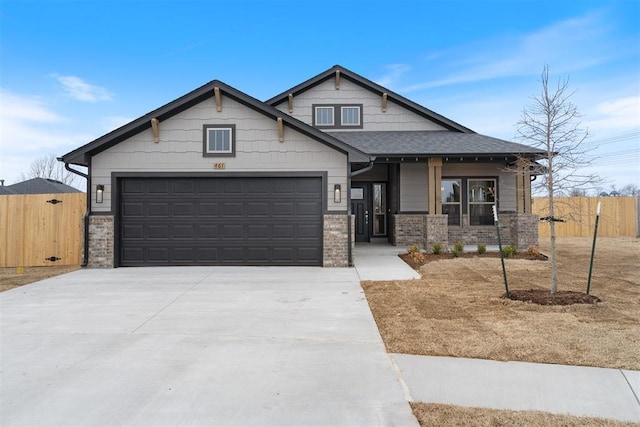 craftsman inspired home featuring brick siding, concrete driveway, an attached garage, and fence