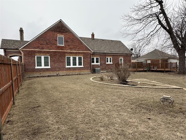 rear view of house featuring central AC and a lawn