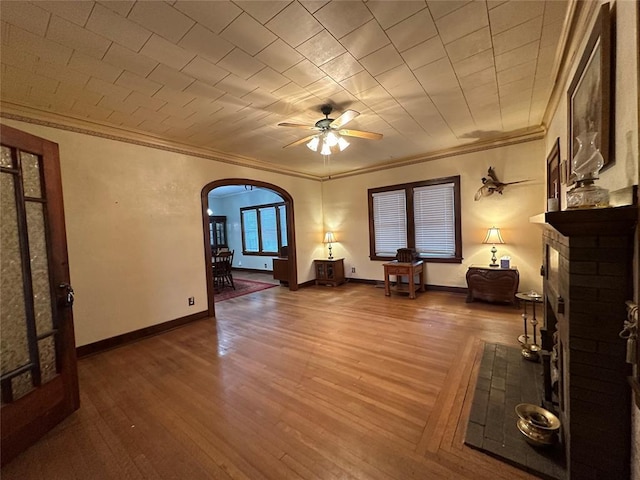 unfurnished living room featuring wood-type flooring, ceiling fan, and crown molding