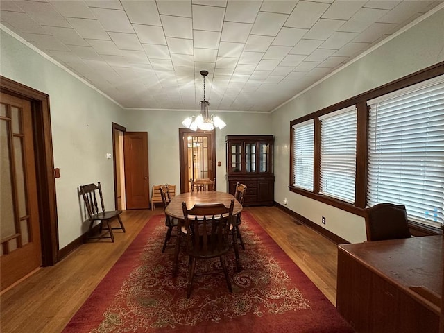 dining area with an inviting chandelier, ornamental molding, and dark hardwood / wood-style floors