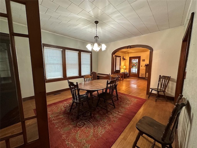 dining area featuring ornamental molding, hardwood / wood-style floors, and an inviting chandelier