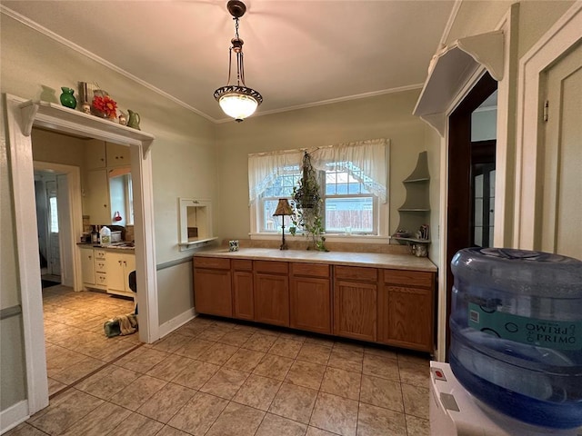 kitchen with sink, decorative light fixtures, ornamental molding, and light tile patterned floors