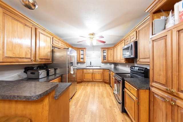 kitchen featuring sink, appliances with stainless steel finishes, kitchen peninsula, ceiling fan, and light hardwood / wood-style floors