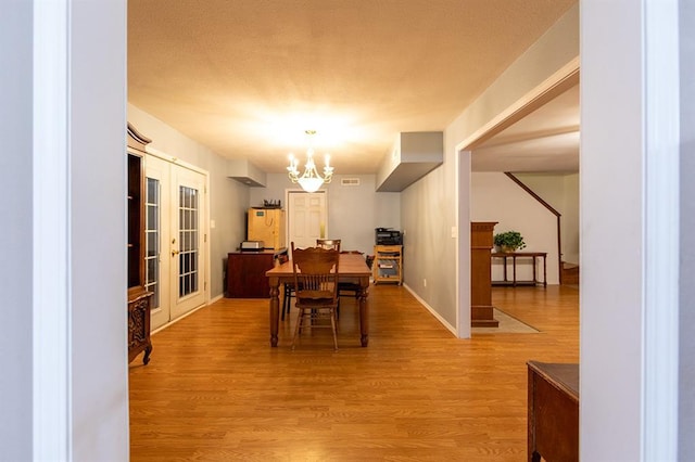 dining area with hardwood / wood-style flooring, a notable chandelier, and french doors