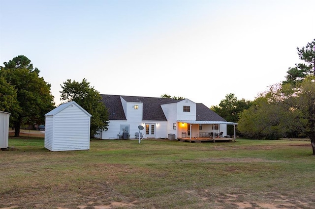 rear view of house featuring a storage shed, a wooden deck, central air condition unit, and a lawn