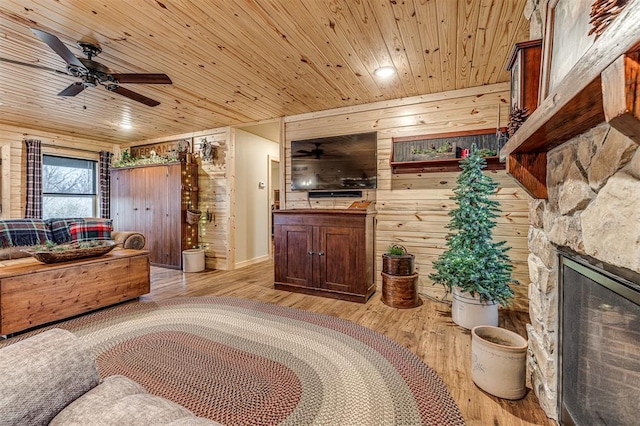 bedroom with a stone fireplace, light wood-type flooring, wood ceiling, and wood walls