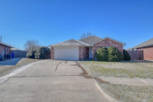 ranch-style home featuring cooling unit, a garage, and a front lawn