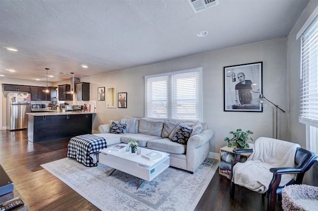 living area featuring visible vents, baseboards, recessed lighting, a textured ceiling, and dark wood-style flooring