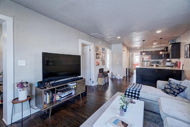 living area with recessed lighting, a textured wall, and dark wood-style flooring