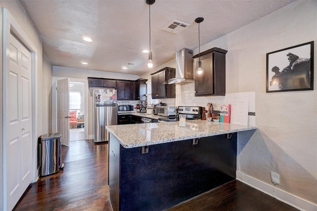 kitchen with extractor fan, dark brown cabinetry, dark wood finished floors, appliances with stainless steel finishes, and a peninsula