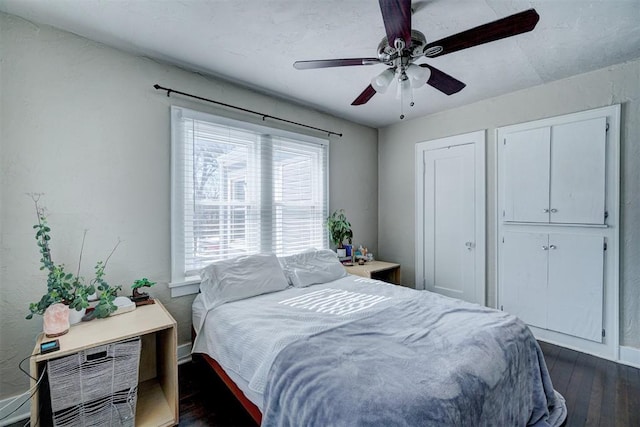 bedroom with baseboards, a ceiling fan, and dark wood-style flooring