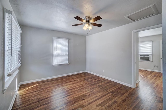 unfurnished room featuring cooling unit, attic access, baseboards, and wood finished floors