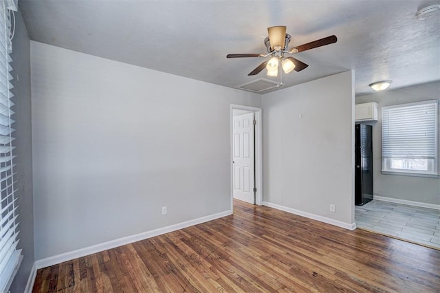 spare room with visible vents, ceiling fan, baseboards, and wood finished floors