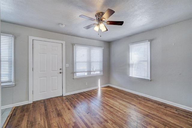 foyer with ceiling fan, a textured ceiling, baseboards, and wood finished floors