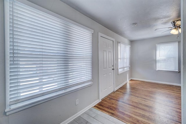 foyer featuring baseboards, wood finished floors, and a ceiling fan