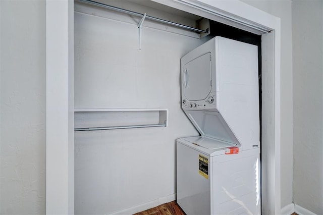 clothes washing area featuring laundry area, stacked washer and clothes dryer, and baseboards