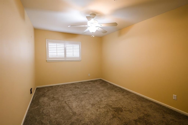 spare room featuring ceiling fan and dark carpet